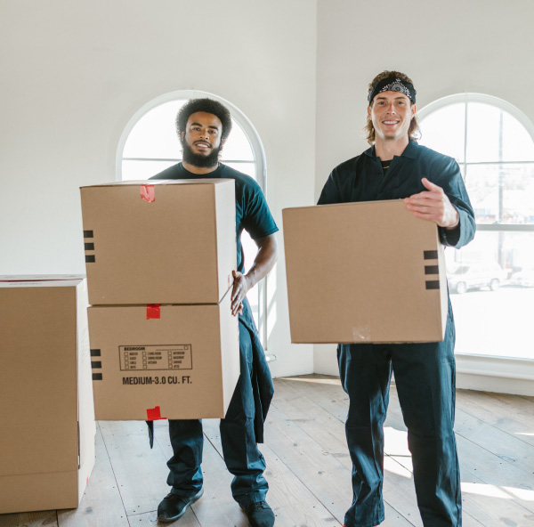 two movers holding boxes smiling at the camera